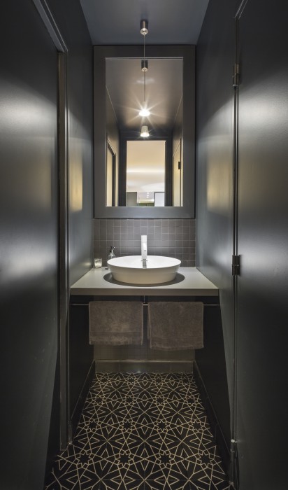 Point d'eau pour invités, au total look noir. Le sol est en carreaux de ciment aux motifs noir et blanc.